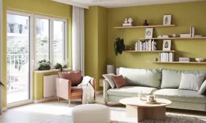 Jasnozielone ściany w salonie dodają energii. Inspiracje do malowania ścian znajdziesz w tej przytulnej aranżacji z wygodną kanapą i fotelem.