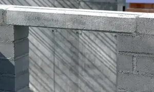 Betonowe nadproże nad otworem w budowie. Cienie ukośnie padają na ścianę z bloczków.