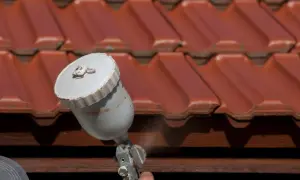 Malowanie dachówki betonowej na czerwono za pomocą pistoletu natryskowego. Odświeżanie dachu.