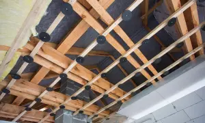 Drewniana konstrukcja pod obniżenie sufitu z wełną mineralną i membraną. Widać system mocowań i izolację.