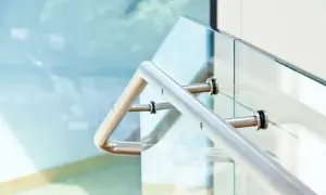 Nowoczesne mocowanie balustrady od czoła do szklanej ścianki. Metalowa poręcz i elementy mocujące.