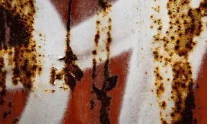 Rdza na samochodzie? Zobacz, jaka farba na rdzę w samochodzie najlepiej poradzi sobie z tym problemem. Tekstura zardzewiałej blachy z białymi i czerwonymi smugami.