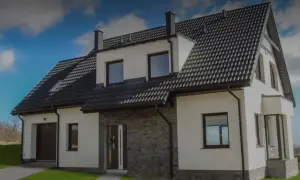 Nowoczesny dom z białymi ścianami, ciemnym dachem i kamienną elewacją.