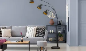Nowoczesny salon z szarą kanapą i stolikiem. Ściany w odcieniach szarego farby, ozdobione makramą.