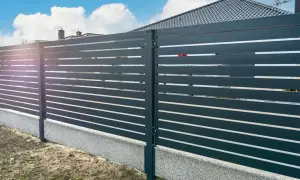 Nowoczesne ogrodzenie z poziomych desek, z betonowym cokołem jako alternatywą dla tradycyjnej podmurówki pod ogrodzenie.