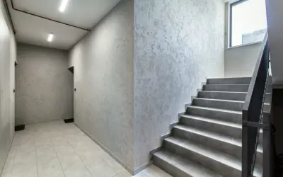 Nowoczesna klatka schodowa z szarymi stopniami i ścianami o ciekawej fakturze. Inspiracja, jak pomalować klatkę schodową w domu.