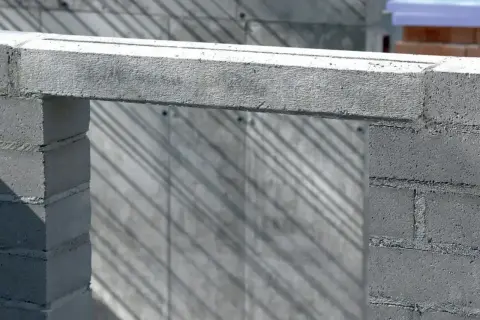 Betonowe nadproże nad otworem w budowie. Cienie ukośnie padają na ścianę z bloczków.