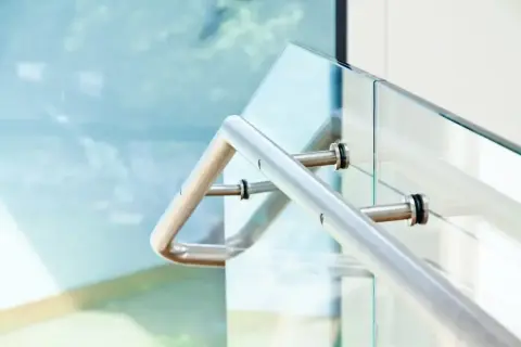 Nowoczesne mocowanie balustrady od czoła do szklanej ścianki. Metalowa poręcz i elementy mocujące.