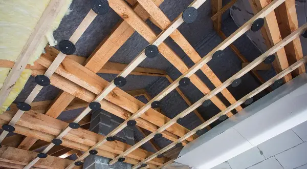Drewniana konstrukcja pod obniżenie sufitu z wełną mineralną i membraną. Widać system mocowań i izolację.
