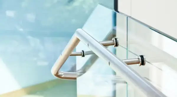 Nowoczesne mocowanie balustrady od czoła do szklanej ścianki. Metalowa poręcz i elementy mocujące.