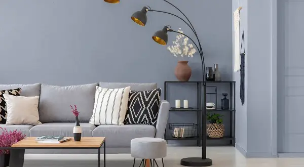 Nowoczesny salon z szarą kanapą i stolikiem. Ściany w odcieniach szarego farby, ozdobione makramą.