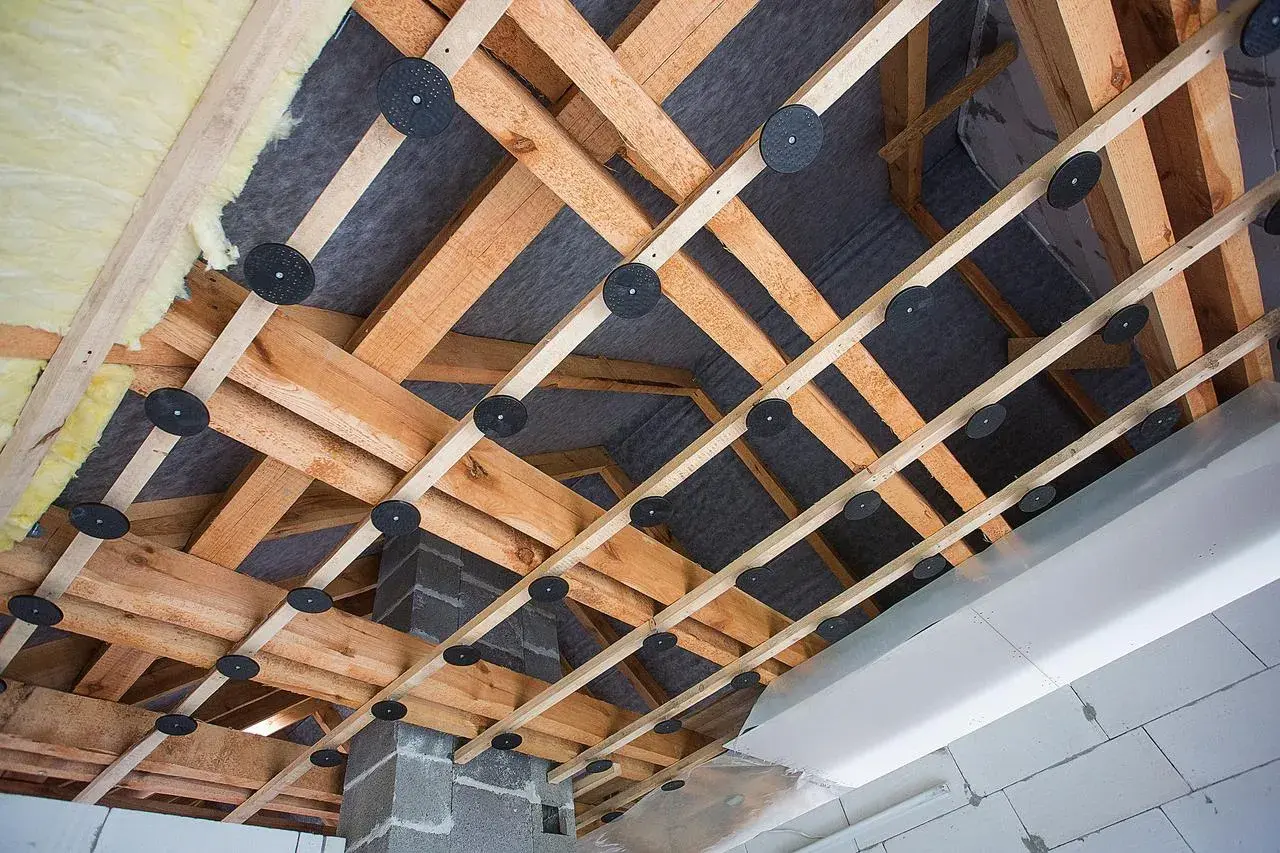 Drewniana konstrukcja pod obniżenie sufitu z wełną mineralną i membraną. Widać system mocowań i izolację.
