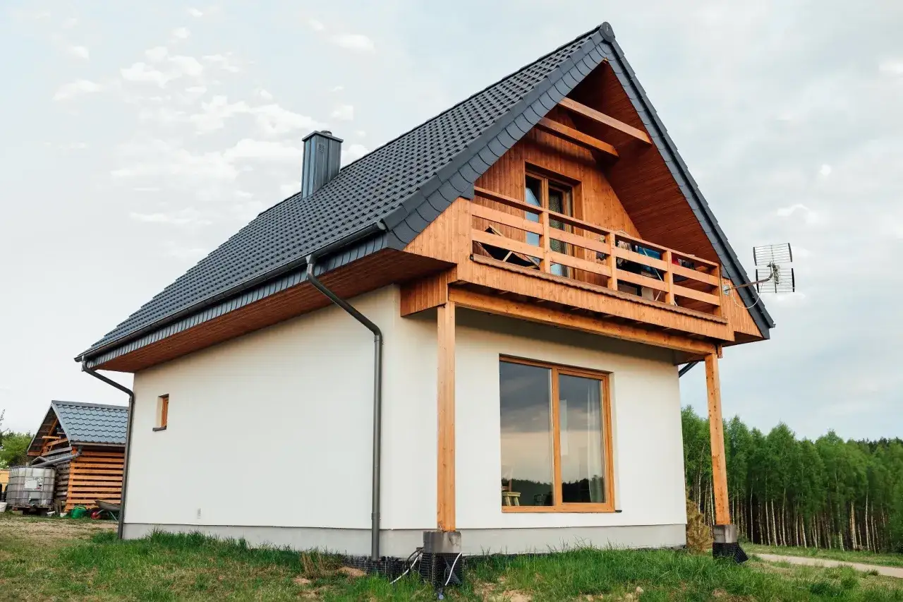 Nowoczesny dom kanadyjski z drewnianą werandą i dużymi oknami, otoczony zielenią.