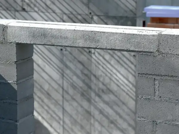 Betonowe nadproże nad otworem w budowie. Cienie ukośnie padają na ścianę z bloczków.