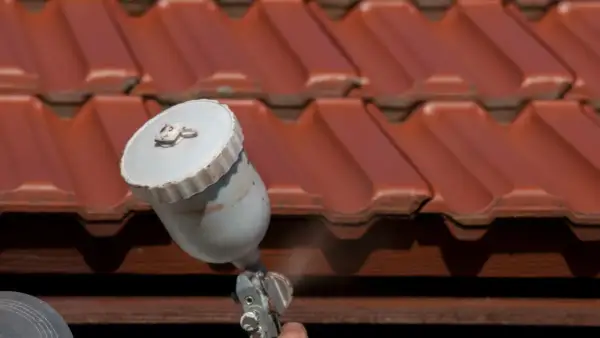 Malowanie dachówki betonowej na czerwono za pomocą pistoletu natryskowego. Odświeżanie dachu.