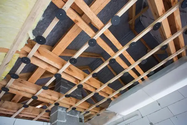 Drewniana konstrukcja pod obniżenie sufitu z wełną mineralną i membraną. Widać system mocowań i izolację.