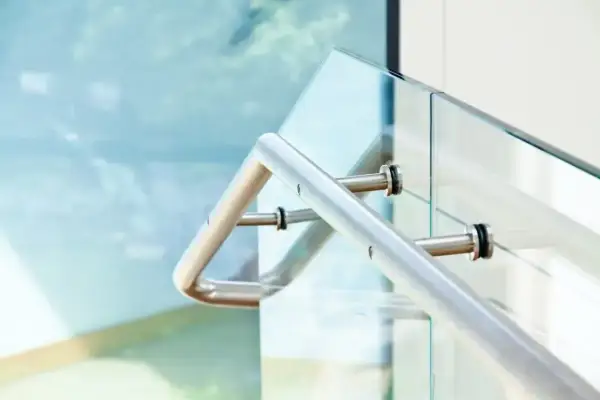 Nowoczesne mocowanie balustrady od czoła do szklanej ścianki. Metalowa poręcz i elementy mocujące.