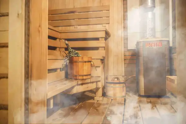 Drewniana sauna z piecem i akcesoriami. Warto wiedzieć, jak zbudować saunę, by cieszyć się relaksem.